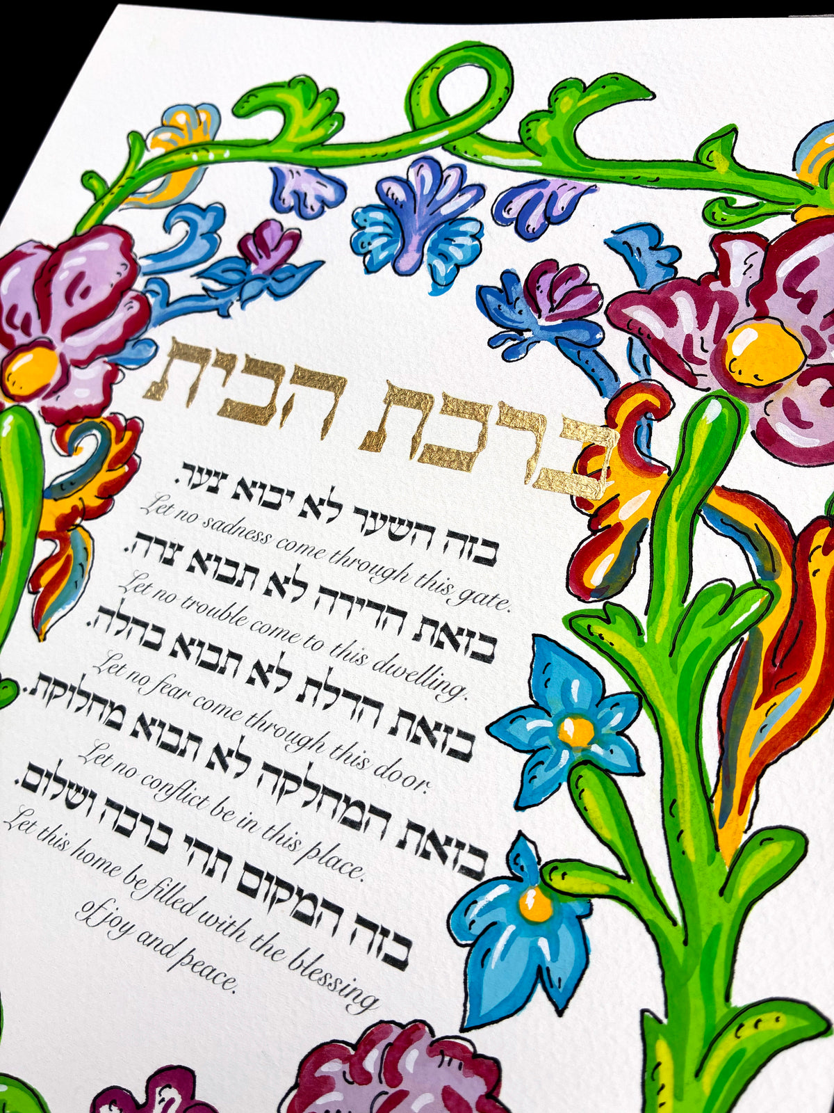Close detail of the hand-lettered gold Hebrew title and floral border