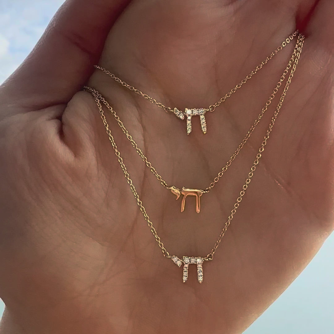 Hebrew Chai diamond necklace shown on a hand in three sizes