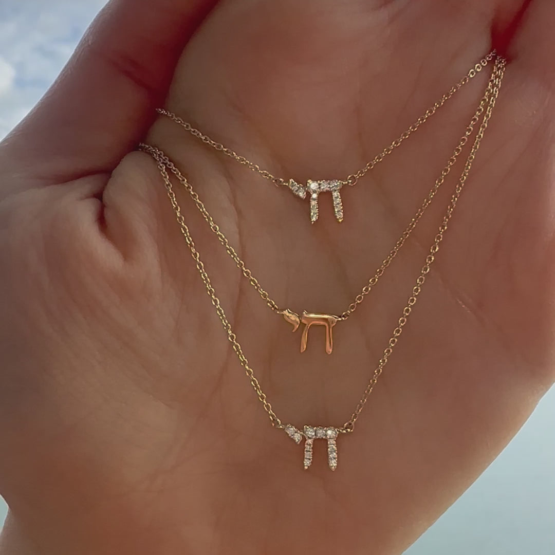 Hebrew Chai gold necklace shown on a hand in three sizes