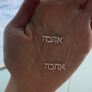 Hebrew Love Diamond Necklace showcasing 'Ahava' in sparkling diamonds on a hand, by Izakov Fine Jewelry.